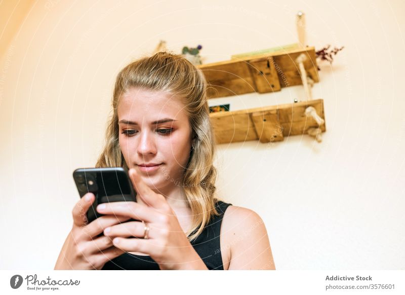 Junge Frau benutzt zu Hause ein Mobiltelefon Smartphone heimwärts benutzend jung lässig Telefon Browsen Nachricht positiv Apparatur Mobile Internet