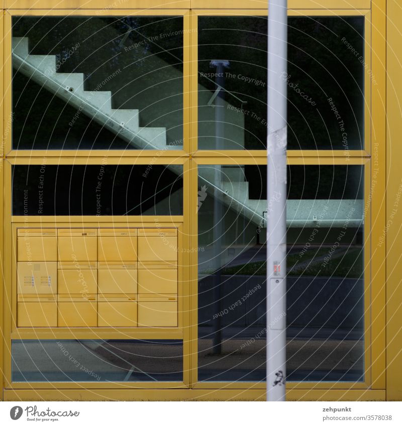 Hauseingang mit Briefkastenanlage und Treppe hinter der Scheibe grafisch rechtwinklig Fensterkreuz Glasscheibe goldfarben grau schwarz randparallel