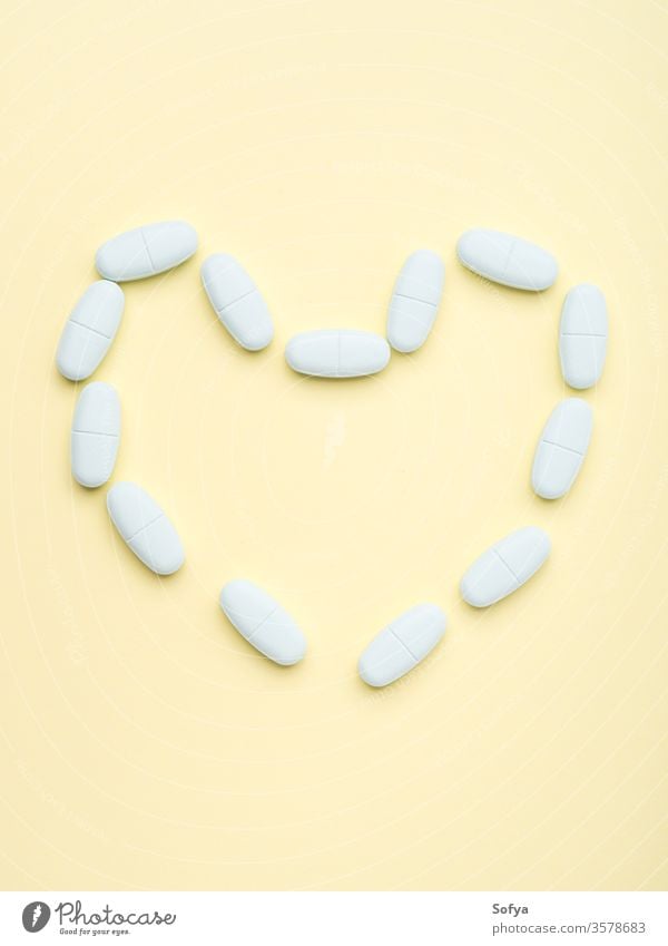 Blaue Pillen in Herzform auf pastellgelb Tablette Konzept Kapsel diätetisch Ergänzung Gesundheit Medizin Sucht Antibiotikum Antioxidans Schönheit Pflege