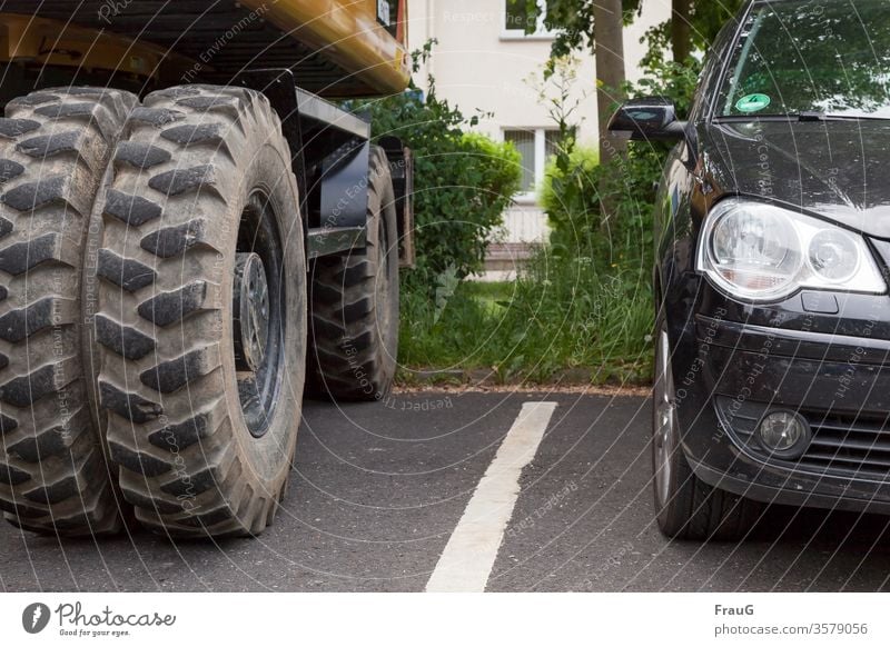 Zwischenräume| große und kleine Reifen PKW Baufahrzeug Bagger Reifenprofil Fahrzeuge groß und klein Straße Markierungslinie geparkt Spiegelung halb Zwischenraum