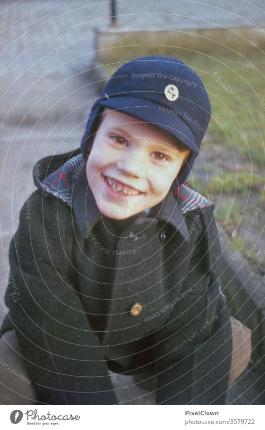 Ein kleiner Junge mit Mütze lacht in die Kamera Kind Spielen Gesicht Kindheit Fröhlichkeit Freude Mensch Lachen retro Kinder