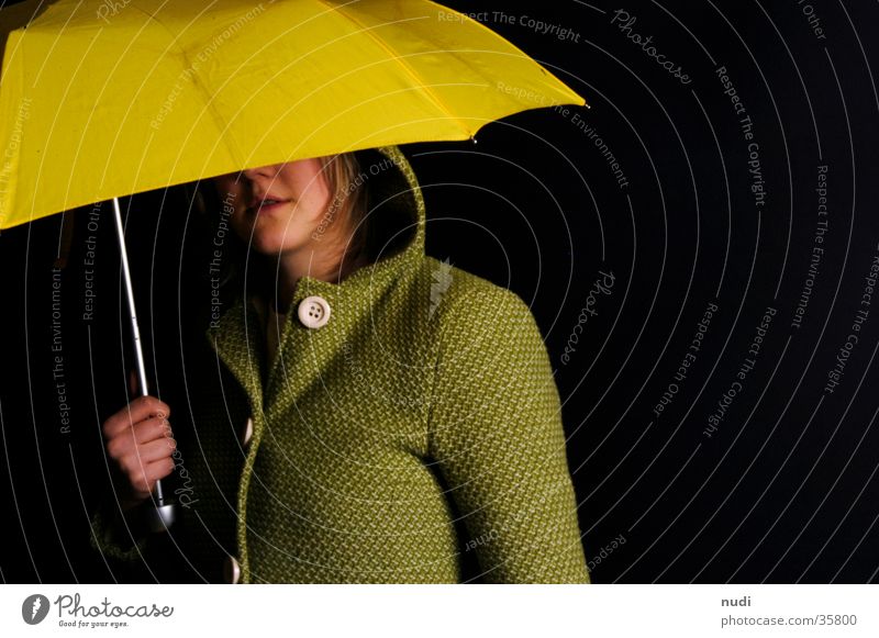 blickkontakt Frau gelb grün schwarz Kapuze Knöpfe Mantel Regenschirm Kopf verstecken Auge