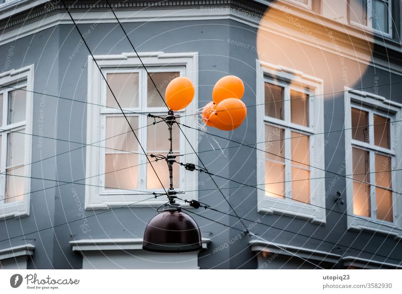 Eine Gruppe Luftballons hängen an einer Oberleitung fest Bewegung festhalten Fester Fassade Haus Hauswand Kreuzung Wand Menschenleer Gebäude Architektur Tag