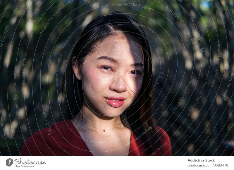 Verträumte junge Asiatin im Park stehend Frau nachdenken Windstille verträumt feminin Mund geöffnet Menschliches Gesicht Halskette ruhig Denken Gelassenheit