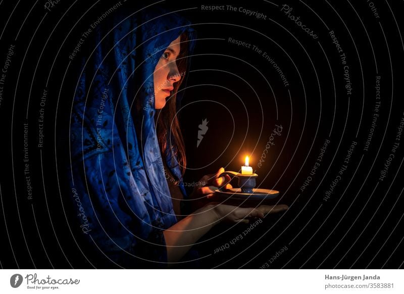 Traurige junge Frau mit Kerze und blauem Kopftuch Gesicht traurig schwarz Porträt frontal Profil ernst Kunst trist Leuchter Hände Flamme Brandwunde Licht