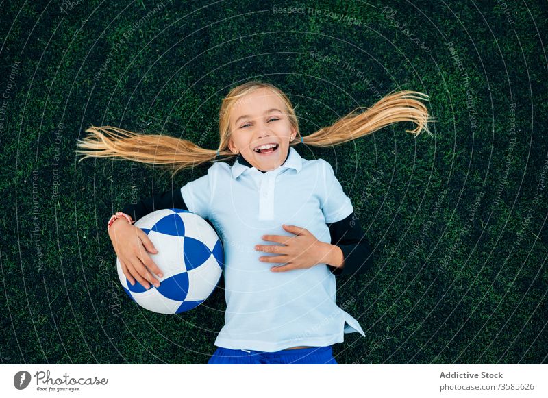 Fröhliche Spielerin mit Fussball entspannt auf dem Rasen Mädchen Fußball Lachen Feld sich[Akk] entspannen Ball Pferdeschwanz Stadion Kind Glück spielerisch