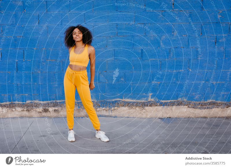 Fröhliche afroamerikanische Frau mit Afro-Frisur in unbeschwerter Pose sich[Akk] bewegen lebhaft pulsierend heiter Lächeln Bewegung Farbe schwarz ethnisch