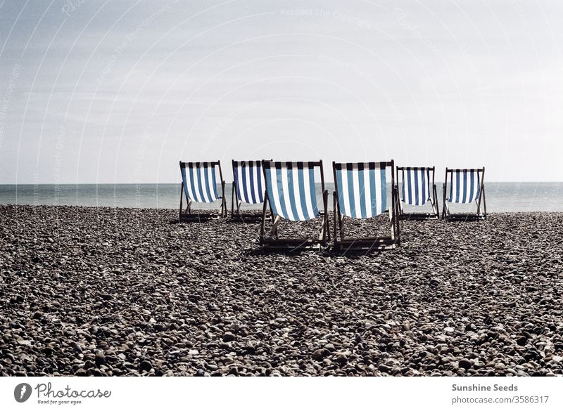 Blau gestreifte Liegestühle an einem britischen Kieselstrand Brighton Großbritannien Niemand leer niemand Miete vereinigtes königreich Küstenstreifen Wasser