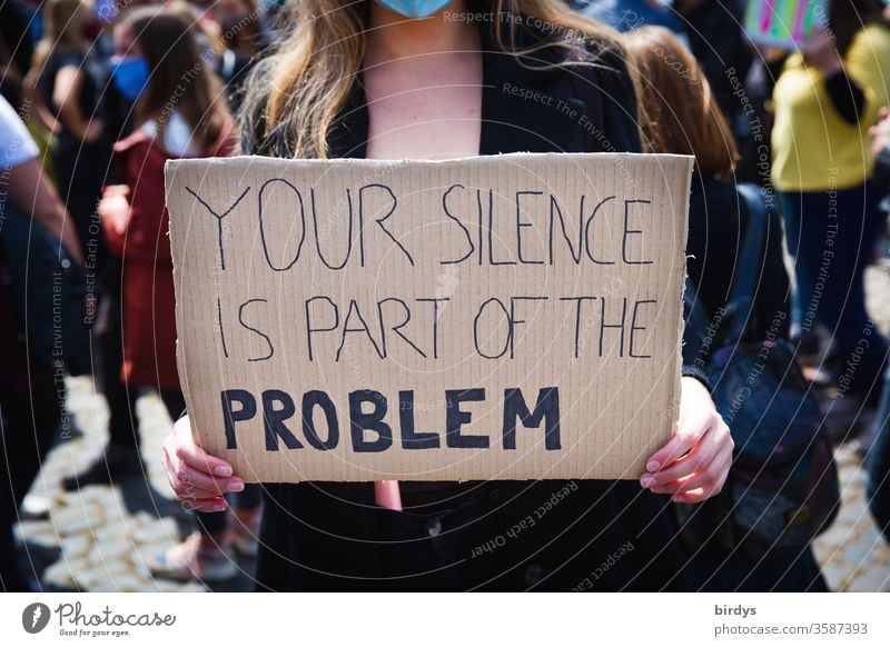 Your silence is part of the problem. Eine junge Frau trägt ein Schild mit der Aufschrift, " dein Schweigen ist Teil des Problems ". Zivilcourage gegen Polizeigewalt , Gewalt, Diskreminierung , sexuelle Übergriffe und Gewalt im Allgemeinen