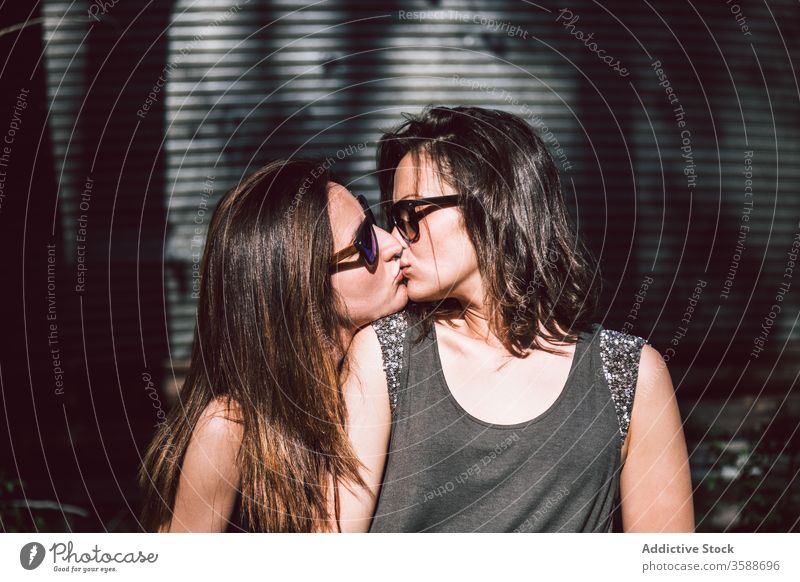 Junges lesbisches Paar küsst sich auf der Straße Frauen Kuss Sommer gleichgeschlechtlich Sommerzeit tagsüber schlendern Spaziergang jung Angebot Sonnenbrille