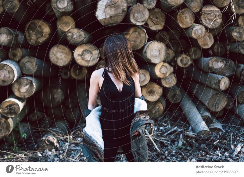 Nicht erkennbare junge Frau gegen große Baumstämme Stil Landschaft rustikal Totholz Deckblatt Fell Wand Rätsel Parka stehen lässig anhaben Tageslicht