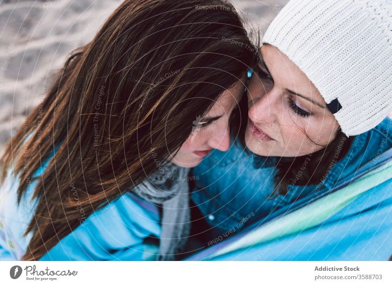 Positives lesbisches Paar ruht sich am Strand aus Inhalt MEER kalt kuscheln Saison warme Kleidung sitzen Sand lgbt Zeit verbringen Frauen schwul jung lässig