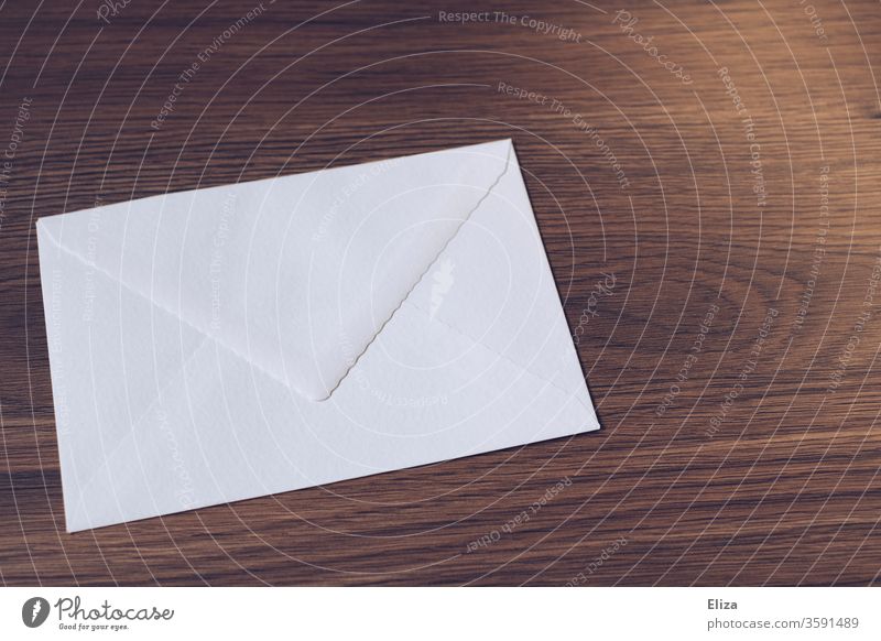 Weißer Briefumschlag auf einem Holztisch. Briefe schreiben. Post. Kommunizieren Papier senden Tisch braun weiß Briefsendung Postsendung