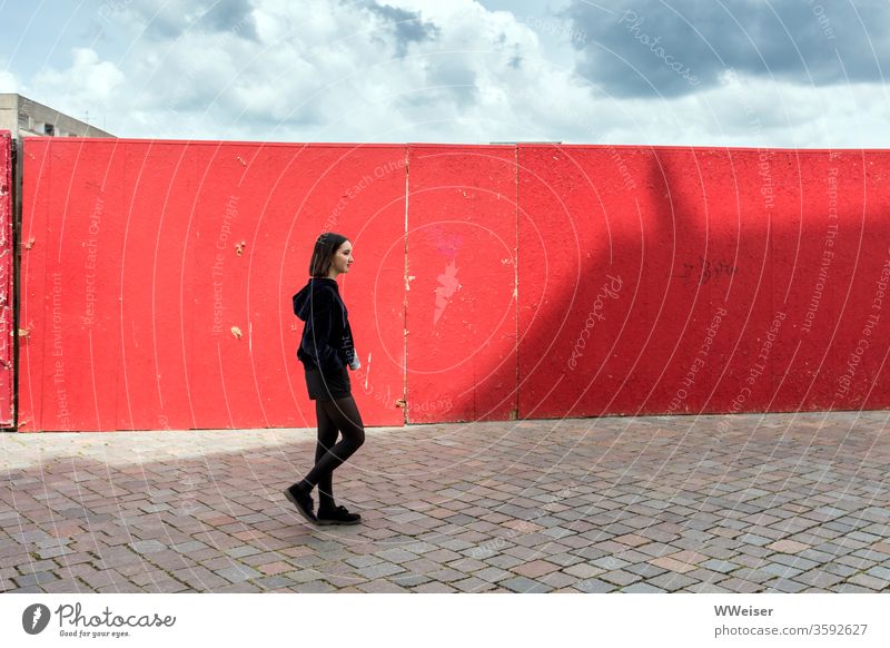 Junge Frau läuft vor roter Wand mit Schatten Mädchen junge Frau Baustelle Himmel Sonne Wolken Stadt Pflaster urban lächeln Lächeln Potsdam Alter Markt Abriss