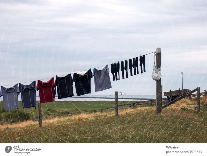 Wäscheleine bei bewölktem Wetter Wäscherei Hemden Socken diagonal trüb trocknen Kleiderhaken hängen Bekleidung Landleben paarweise Aus Wechsel hallig Nordsee