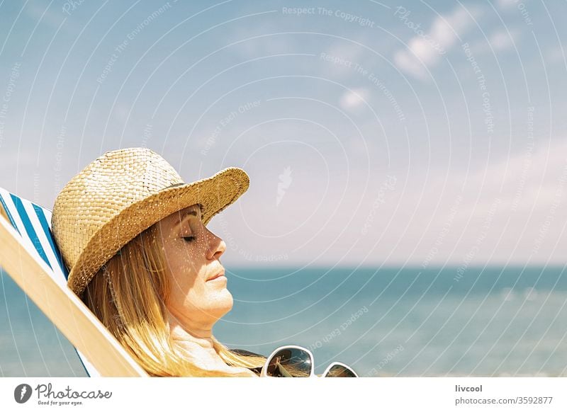 frau ruht auf einem Liegestuhl in der Sonne, französische Küste Surfer Frau Borsalino-Hut genießend Sommersonne Menschen aussruhen blond MEER Lifestyle Porträt