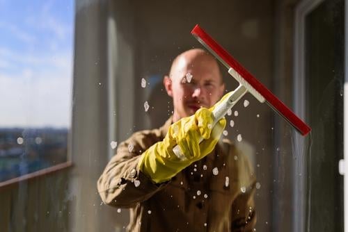 Mann wäscht Fenster in gelben Gummihandschuhen Raumpfleger Sauberkeit heimisch Arbeit Glas Rakel Hausarbeit Waschen Wasser Person Hygiene heimwärts durchsichtig