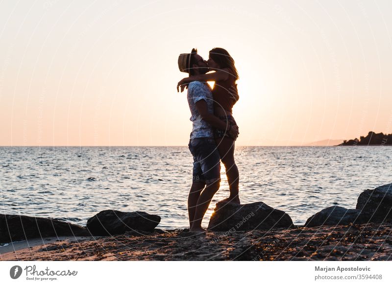 Junges Paar küsst sich bei Sonnenuntergang am Strand jung Mann Frau Kuss Küssen Liebe MEER Meer Flitterwochen Liebespaar Jungvermählte Romantik romantisch