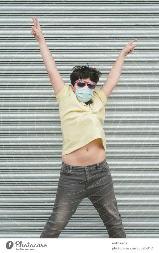 glückliches Kind mit medizinischer Maske springt auf die Straße medizinische Maske covid-19 Junge Glück springen springend Spaß Feiertage Lifestyle Fröhlichkeit