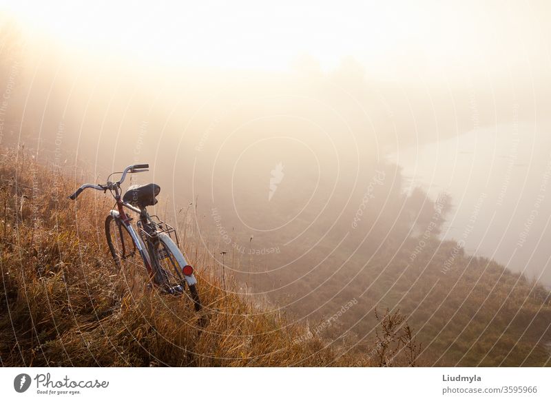 Ein altes Fahrrad am frühen Morgen in der Landschaft und im Landschaftsnebel.  Fahrrad-Reisekonzept. Platz für Text männlich Geschwindigkeit Mann aktiv Nachlauf