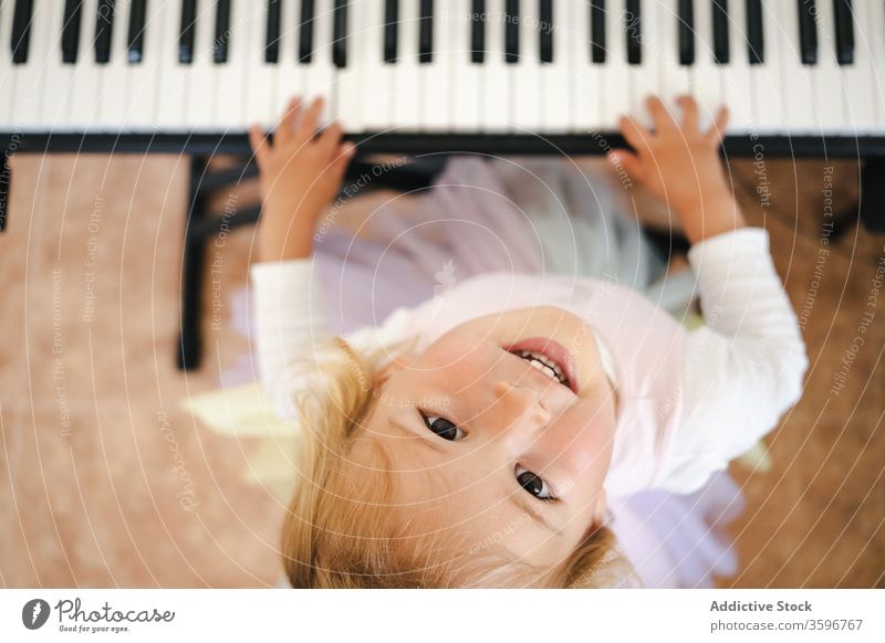 Lachendes Mädchen spielt Klavier und schaut in die Kamera heimwärts Synthesizer spielen Spaß Glück lernen Lächeln Kindheit Kleinkind niedlich Musik Klasse Rock