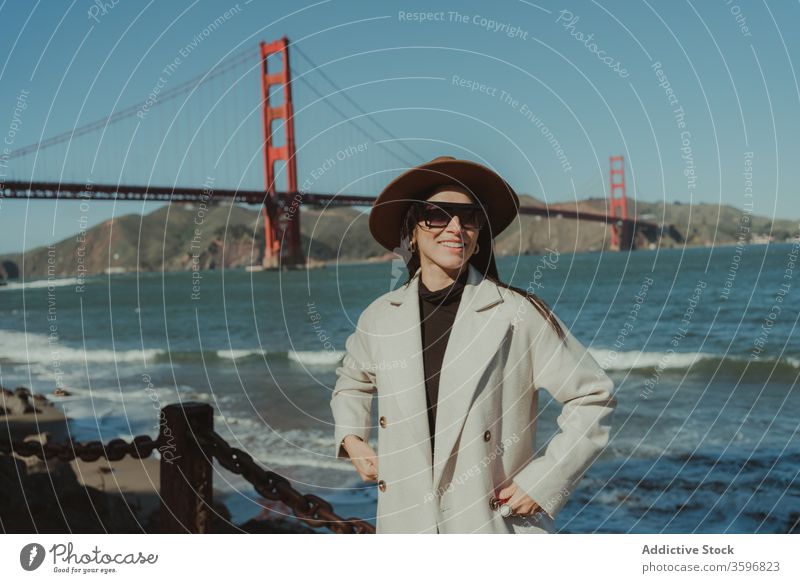 Stilvolle Frau am Wasser stehend mit Brücke im Hintergrund trendy reisen Glück Lächeln jung genießen Tourismus San Francisco Goldenes Tor Kalifornien amerika