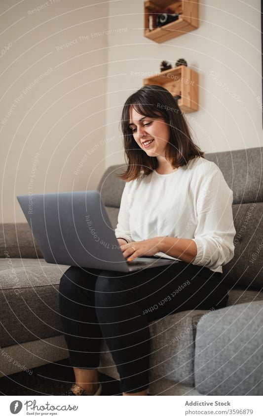 Weibliche Freiberuflerin mit Laptop zu Hause multitask Unternehmer Frau Lächeln benutzend Apparatur Glück Projekt Browsen selbstbewusst Sofa abgelegen Gerät