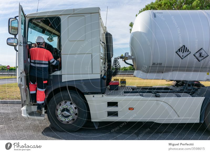 Fahrer eines Gefahrgut-Tankwagens steigt mit den beiden Griffen sicher ins Fahrerhaus Lkw-Fahrer gefährliche Güter Mann hohe Sichtbarkeit adr Kabine Brennstoff