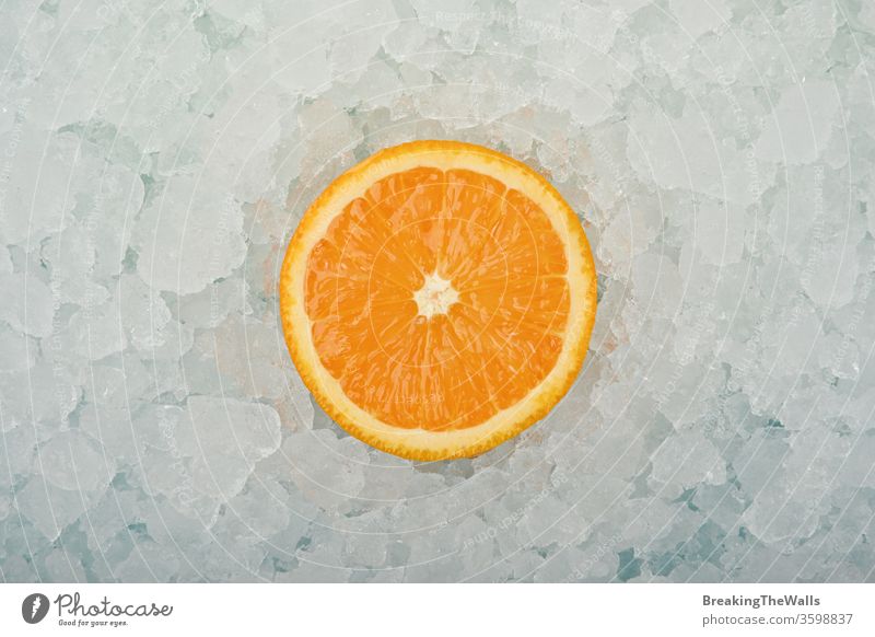 Frische Orangenschnittscheibe über zerstoßenem Eis orange eine Hälfte geschnitten Scheibe frisch zerdrückt Hintergrund Nahaufnahme blau weiß kalt gefroren
