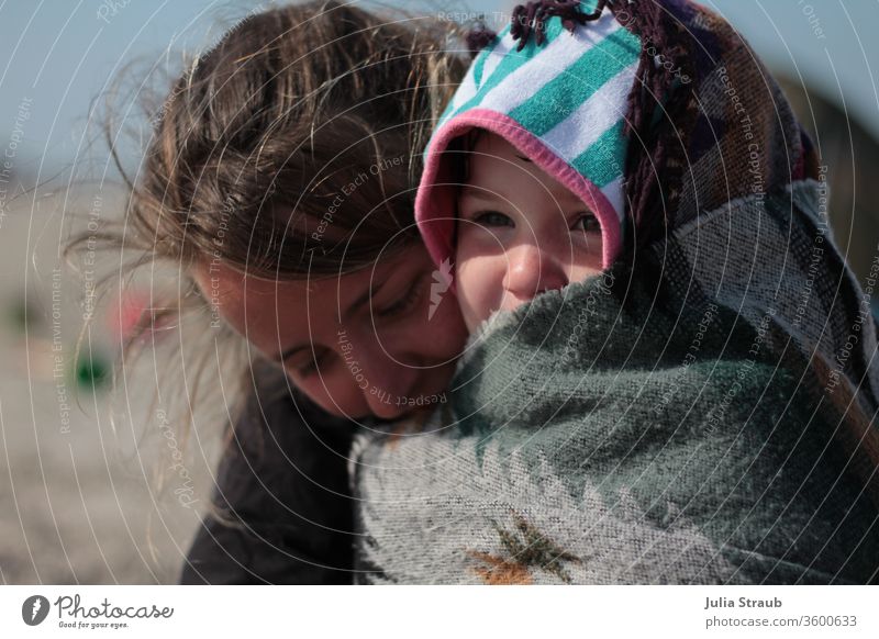Frau wärmt kleines Mädchen mit einer Decke Kind gestreift Kapuzenpullover Handtuch umhüllt eingewickelt Ethnomuster grün grau zackig kalt wärmen drücken Umarmen