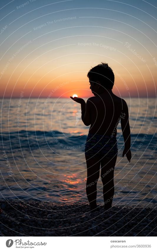 Kleiner Junge spielt mit der Sonne am Strand bei Sonnenuntergang aktiv schön sorgenfrei heiter Kind Kindheit Küste Küstenstreifen Abend Spaß Griechenland Hand