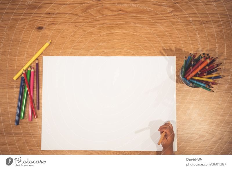 Kind hält vor einem weißen Blatt Papier einen Buntstift in der Hand Buntstifte Stifte farben farbenfroh malen kreativ Kreativität Zettel Textfreiraum zeichnen