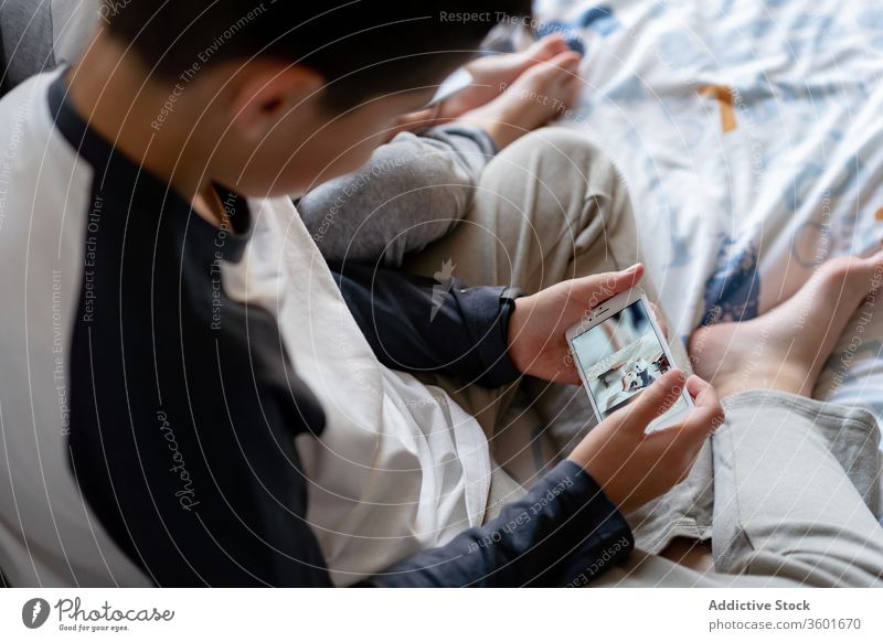 Geschwisterkulturen mit Smartphone am Bett Geschwisterkind benutzend zuschauen Karikatur sich[Akk] entspannen heimwärts Kinder Bruder gemütlich Kindheit Gerät