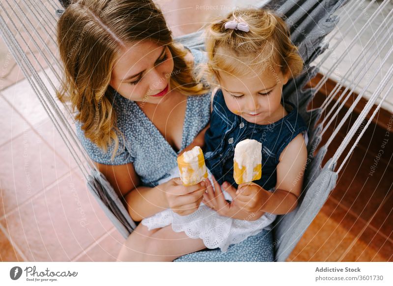 Glückliches kleines Mädchen und Frau mit hausgemachten Eis am Stiel Mutter Tochter Umarmung Stieleis selbstgemacht Kies genießen heiter Sommer Terrasse Lächeln