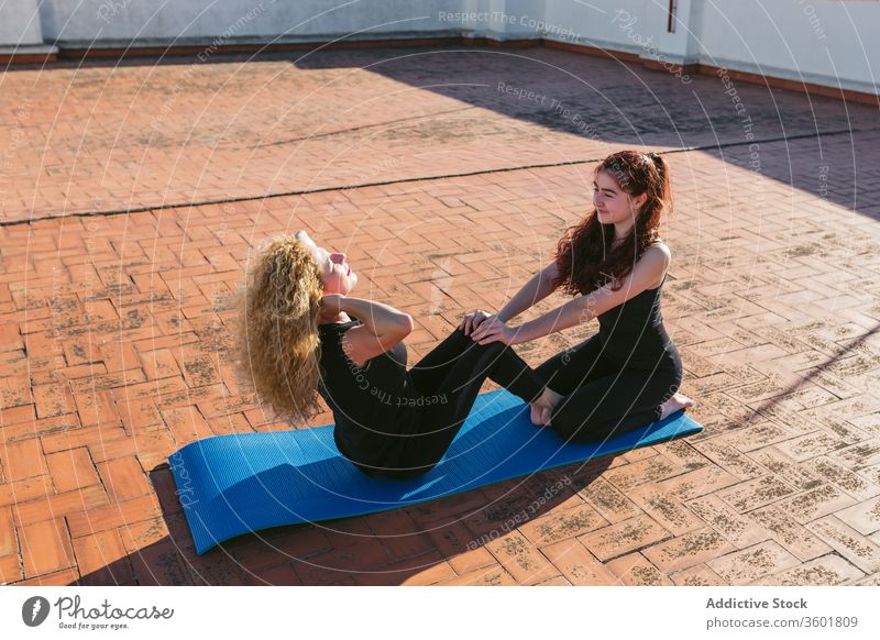 Frauen praktizieren Partner-Yoga auf dem Dach Zusammensein Dachterrasse Terrasse üben Pose positionieren sitzen Kerngehäuse Gleichgewicht abstützen Akro-Yoga