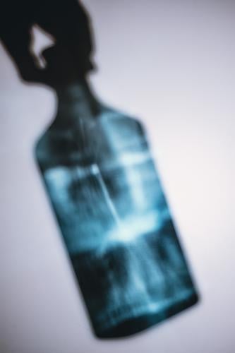 Griff zur Flasche Gin blau Lichtspiel Schatten Hand festhalten Glas Getränk Alkohol trinken