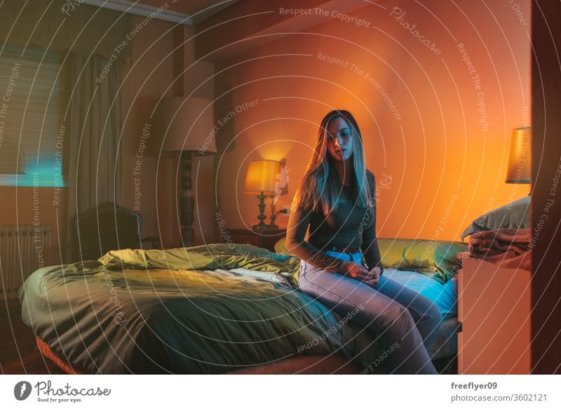 Junge Frau sitzt traurigerweise spät nachts allein auf dem Bett Porträt Nacht Quarantäne Depression Kopfkissen Coronavirus covid-19 Isolation selbstisoliert