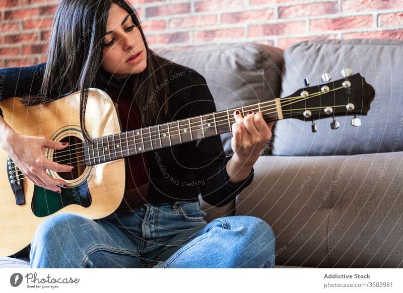 Frau spielt Gitarre und lernt mit Online-Kursen Musik Lifestyle im Innenbereich Lernen Spielen E-Learning Menschen Gitarrenspieler Erwachsener