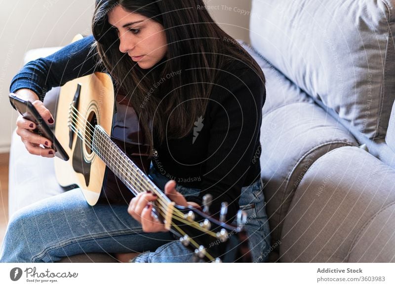 Frau spielt Gitarre und lernt mit Online-Kursen Musik Lifestyle im Innenbereich Lernen Spielen E-Learning Menschen Gitarrenspieler Erwachsener