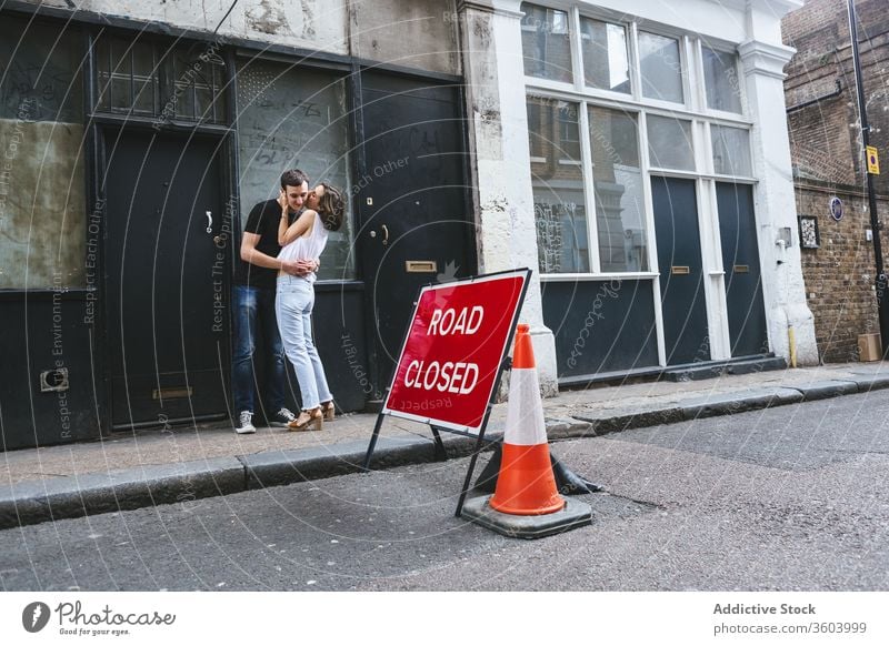 Fröhliches Paar umarmt und küsst sich auf der Straße Umarmung Kuss schlendern Großstadt Angebot schäbig Gebäude Straßenrand London England