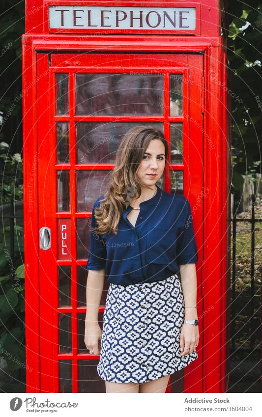 Charmante Frau in der Nähe der roten Telefonzelle auf der Straße Telefonhaus charmant Großstadt altmodisch Tradition retro Kultur London England Großbritannien
