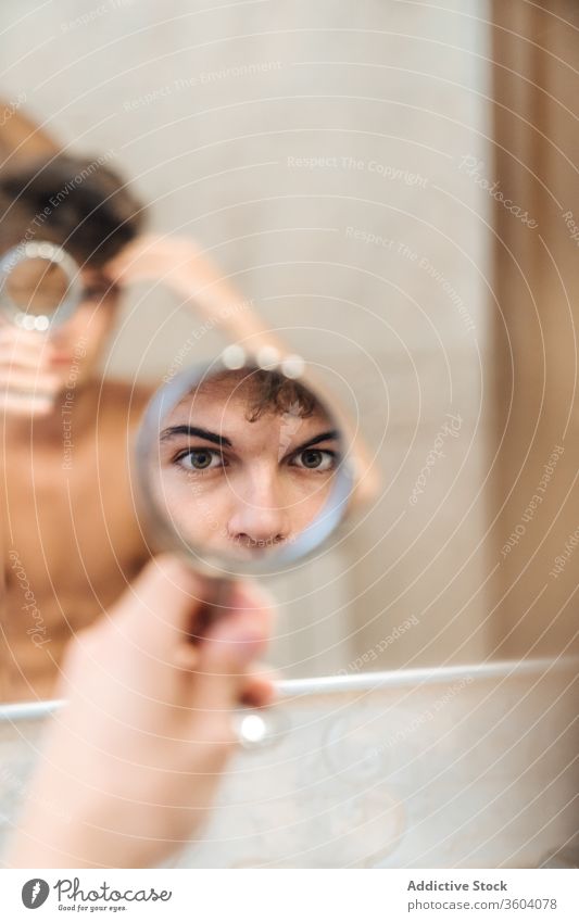Hübscher Mann beim Blick in den Spiegel Bad Auge Morgen heimwärts hell ernst Routine täglich frisch männlich stehen Hygiene Stil Pflege Sauberkeit Zeitgenosse