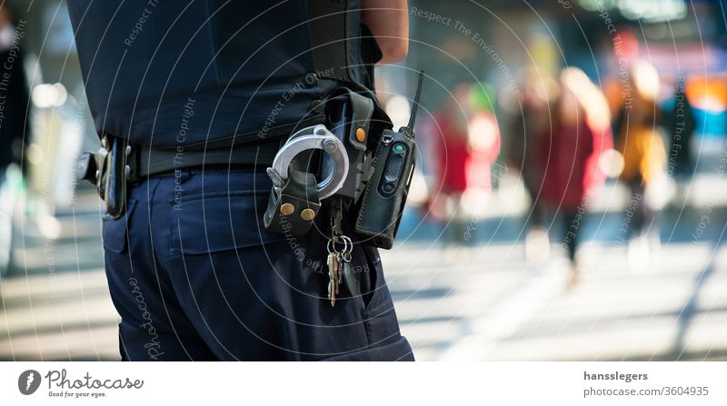 Polizist mit verschwommenen Personen im Hintergrund Polizei zuschauend Schutzmann Handschellen Menge Straße Sicherheit Großstadt Kontrolle cop Verbrechen