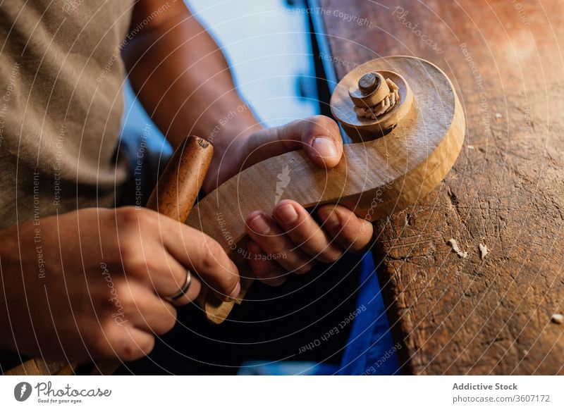 Zuschneider, der den Geigenkopf mit dem Meißel in einem modernen Arbeitsstudio herstellt Schnitzereien Beitel Kunsthandwerker Werkzeug Handwerk Werkstatt