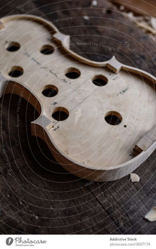 Resonanzboden einer handgefertigten Geige auf schäbiger Holzoberfläche im Arbeitsraum Prozess Werkstatt Golfloch Werkzeug Handwerk Sägemehl Instrument hölzern