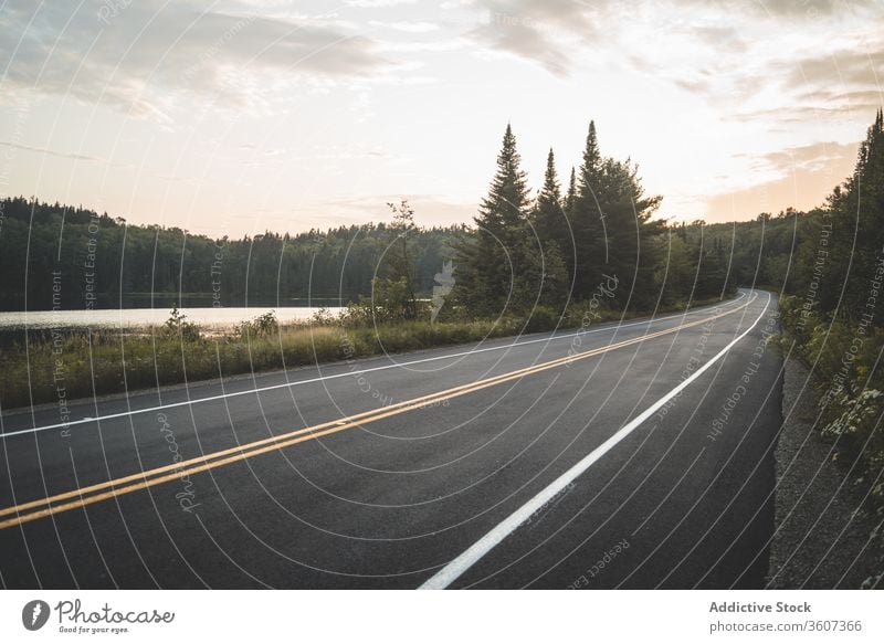 Asphaltstrasse in der Nähe von See und Wald am Abend Straße Sonnenuntergang Himmel wolkig Natur Nationalpark la mauricie Quebec Kanada friedlich grün Windstille
