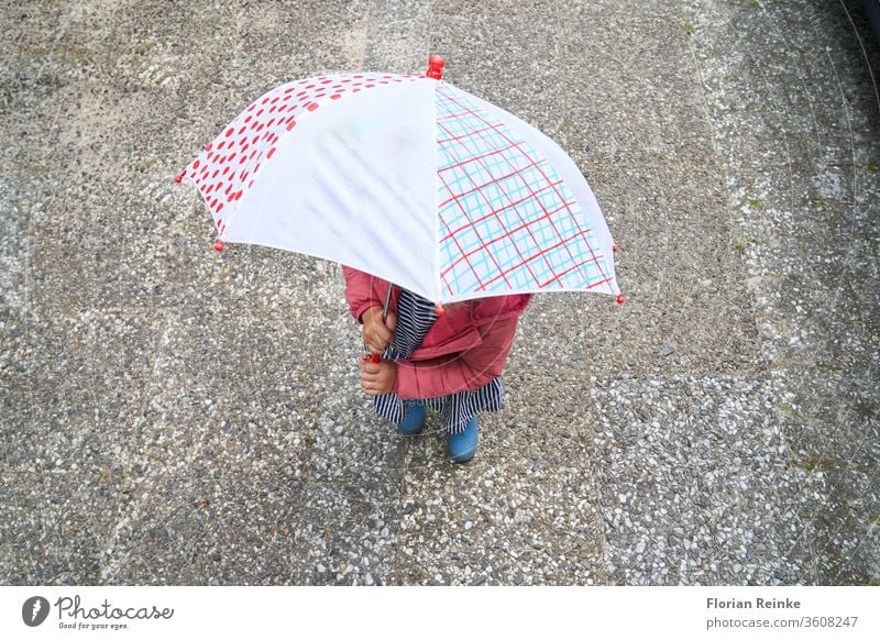 vierjähriges Mädchen mit Regenschirm und Gummistiefeln Herbst Schönheit blond Stiefel heiter Kind Großstadt Farbe Kleid Frau Spaß lustig Fröhlichkeit springen