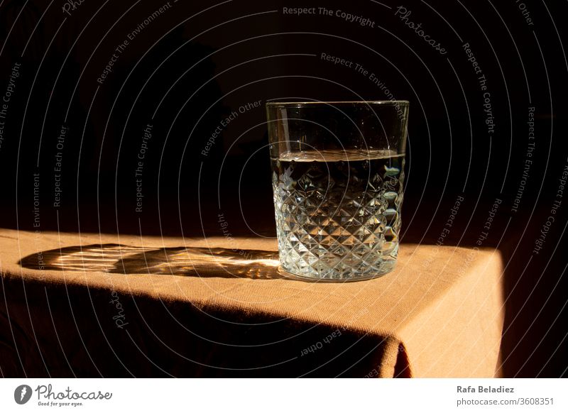 Mit Wasser gefülltes Glas auf brauner Tischdecke Mahlzeit Glasflasche Apothekenglas forschen Sonnenlicht zu Hause Brille trinken Licht