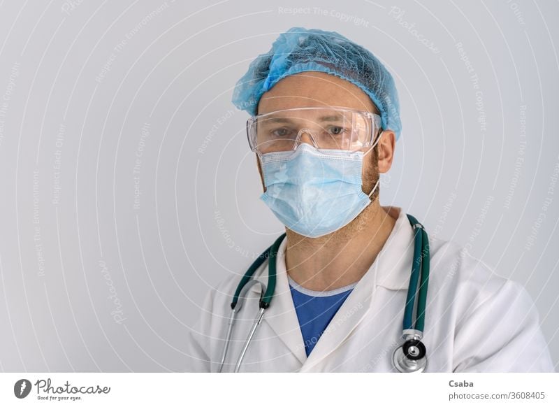 Porträt eines Arztes mit Gesichtsmaske und Schutzbrille Blick müde Auge Brille Mundschutz Stethoskop Krankenhaus Mann COVID19 Coronavirus Gesundheitswesen