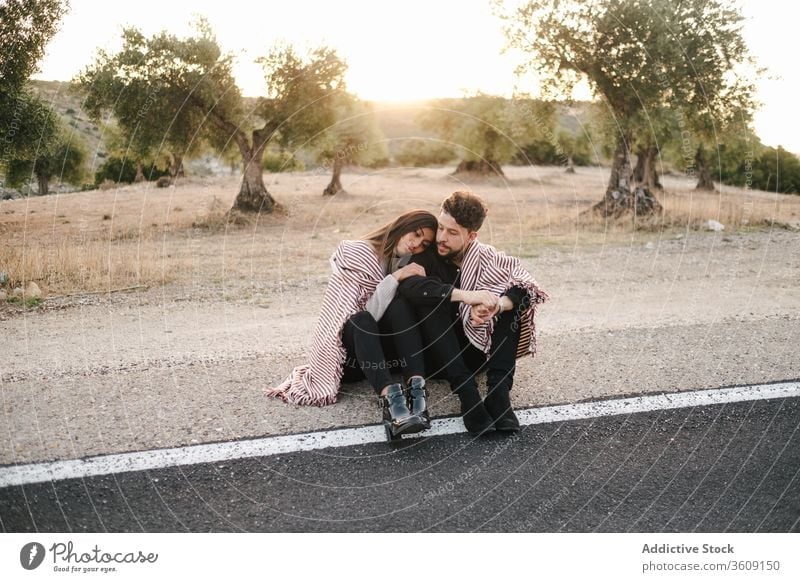 Liebespaar umarmt sich am Straßenrand Paar Umarmung sitzen Sonnenuntergang Landschaft spektakulär Zusammensein Partnerschaft natürlich romantisch Umarmen Natur